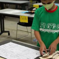 A camper begins making his wooden airplane